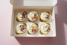 Load image into Gallery viewer, Six cupcakes with white frosting and colorful sprinkles in a box with pink background.