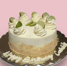 Load image into Gallery viewer, Birthday key lime cake with lime slices and whipped cream on a silver cake stand.