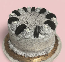 Load image into Gallery viewer, Oreo cookie cake with white frosting and Oreo cookies on a clear cake stand.