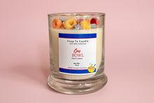 Load image into Gallery viewer, Candle in  glass jar with fruit cereal design  with a label on pink background

